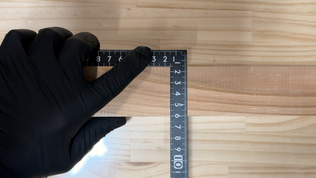 作業台の上で、曲尺を使って正確に直線を引く様子