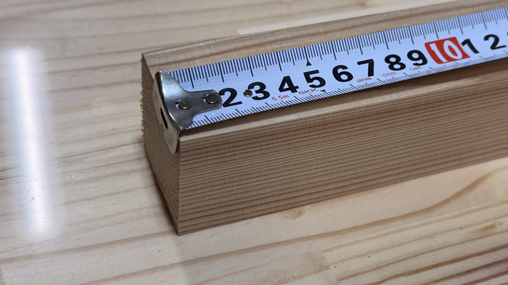 木材の端にコンベックスのL字を引っ掛けています